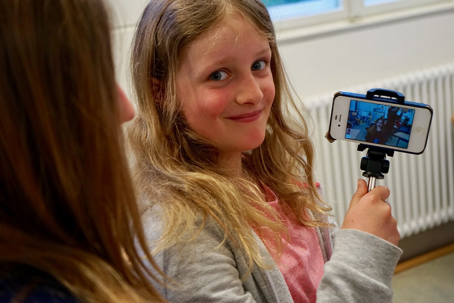 Jetzt: Schülerinnen bei Dreharbeiten mit dem Smartphone - War: Grundschüler bei Dreharbeiten im Klassenraum