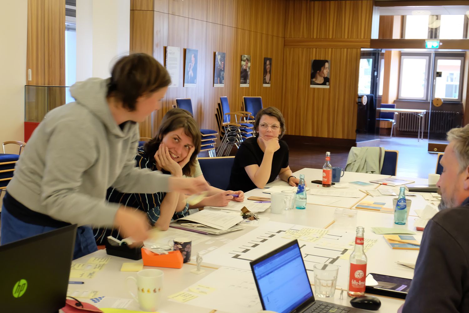 Das Foto zeigt mehrere Personen an einem Tisch sitzend, die sich gemeinsam in einer Workshopsituation befinden.