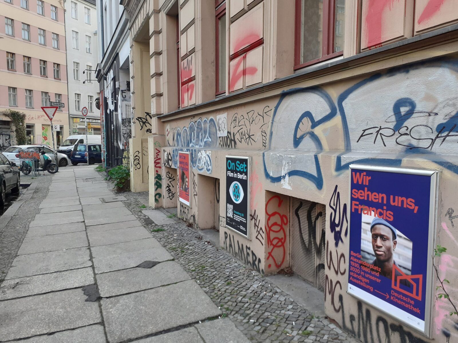 Das Foto zeigt mehrere Werbeplakate an einer Hauswand in Berlin-Kreuzberg. Eins davon ist ein Werbeplakat für die App "On Set". Es dient als Marker zum Auslösen der AR-Elemente in der App.
