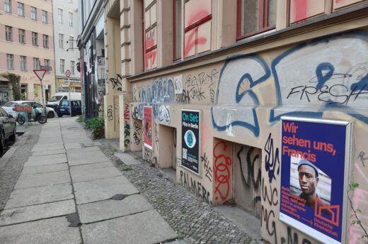 Das Foto zeigt mehrere Werbeplakate an einer Hauswand in Berlin-Kreuzberg. Eins davon ist ein Werbeplakat für die App 