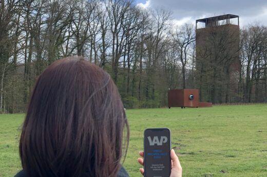 Eine Frau öffnet die Handy-App VAP Varus. Archäologie. Park.