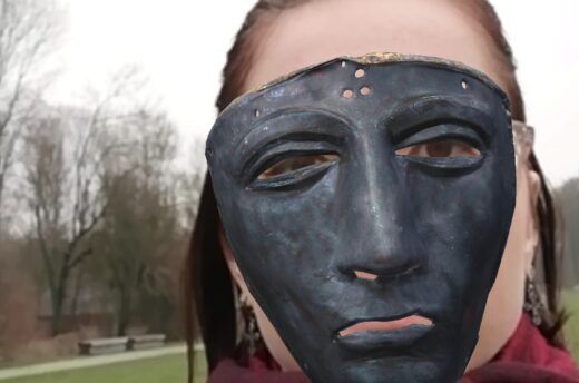 Das Bild zeigt einen Screenshot aus einer App, eine Gesichtsmaske aus der Römerzeit in Augmented-Reality Technologie, die vor einem Gesicht zu sehen ist.