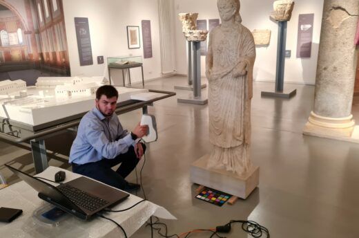 Ein Mann scannt mit einem 3D-Handmessgerät in einem Museum eine römische Statue ein.