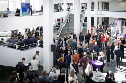 In der unteren Halle des Kulturforums lauschen viele Menschen einer Rede