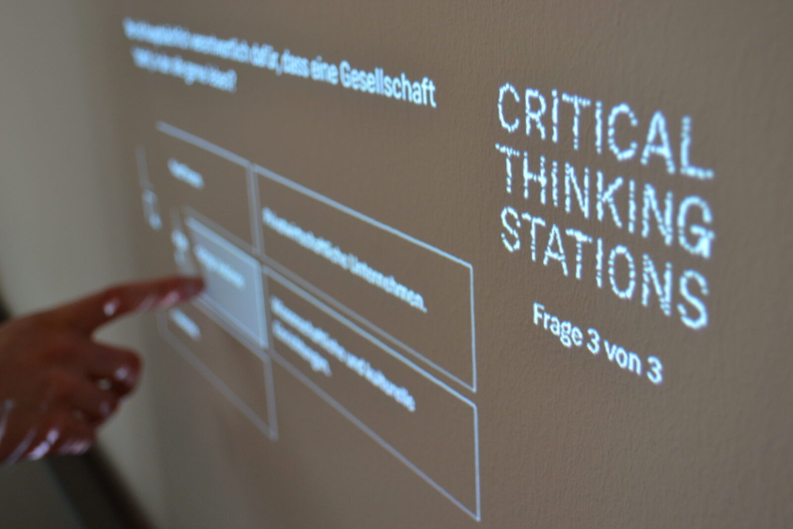 Die "Critical Thinking Stations" stellen die Museumsbesucher*innen vor diverse migrationsbezogene Fragen. Im Bild wählt eine Frau zu einer dieser Fragen im Multiple-Choice-Verfahren eine Antwort per Fingerzeig aus.