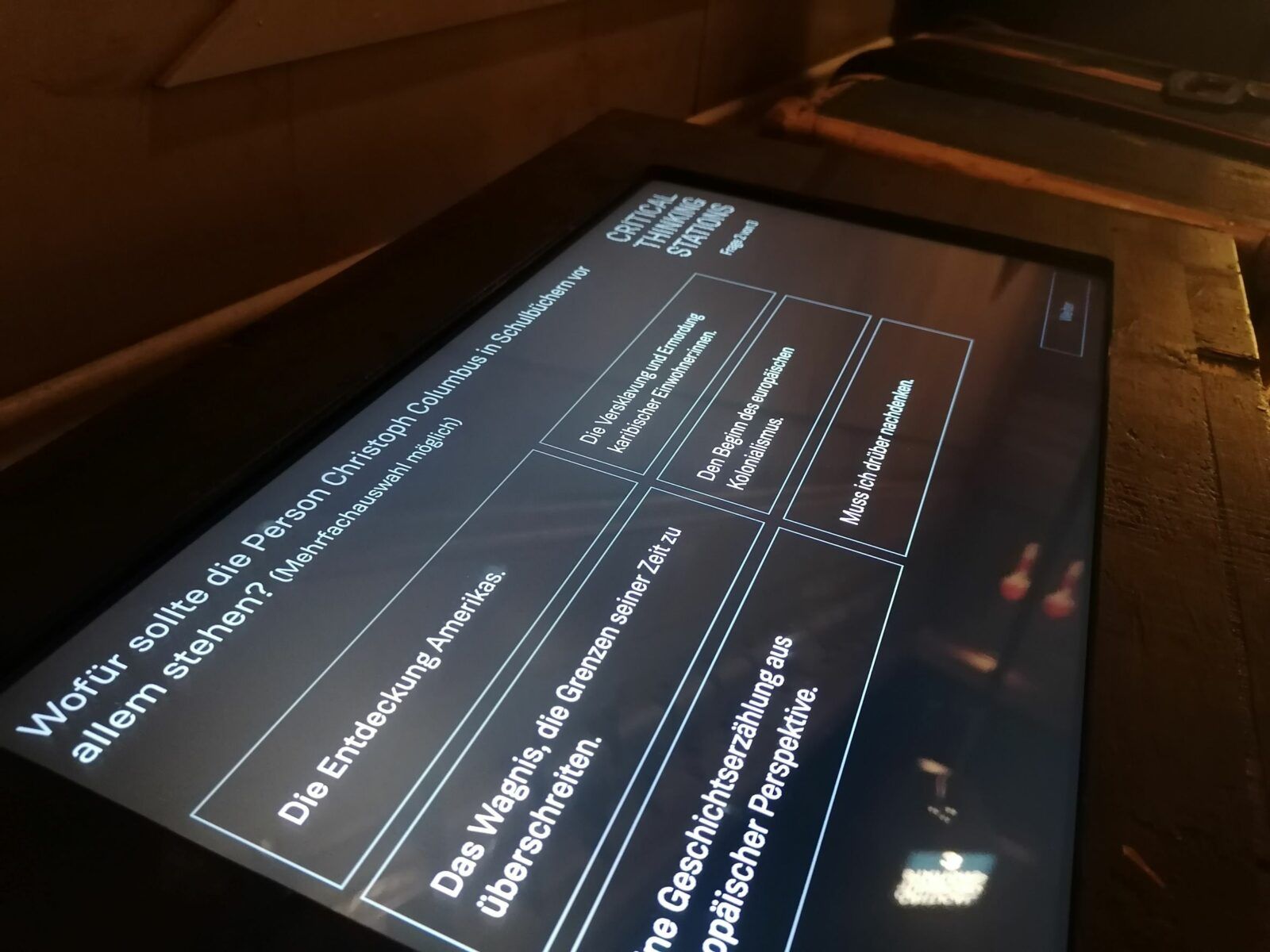 Auf dem Screen einer CTS-Station ist die Frage zu lesen, wofür die Person Christoph Columbus in Schulbüchern vor allem stehen sollte. Darunterstehend sind sechs Antwortoptionen.