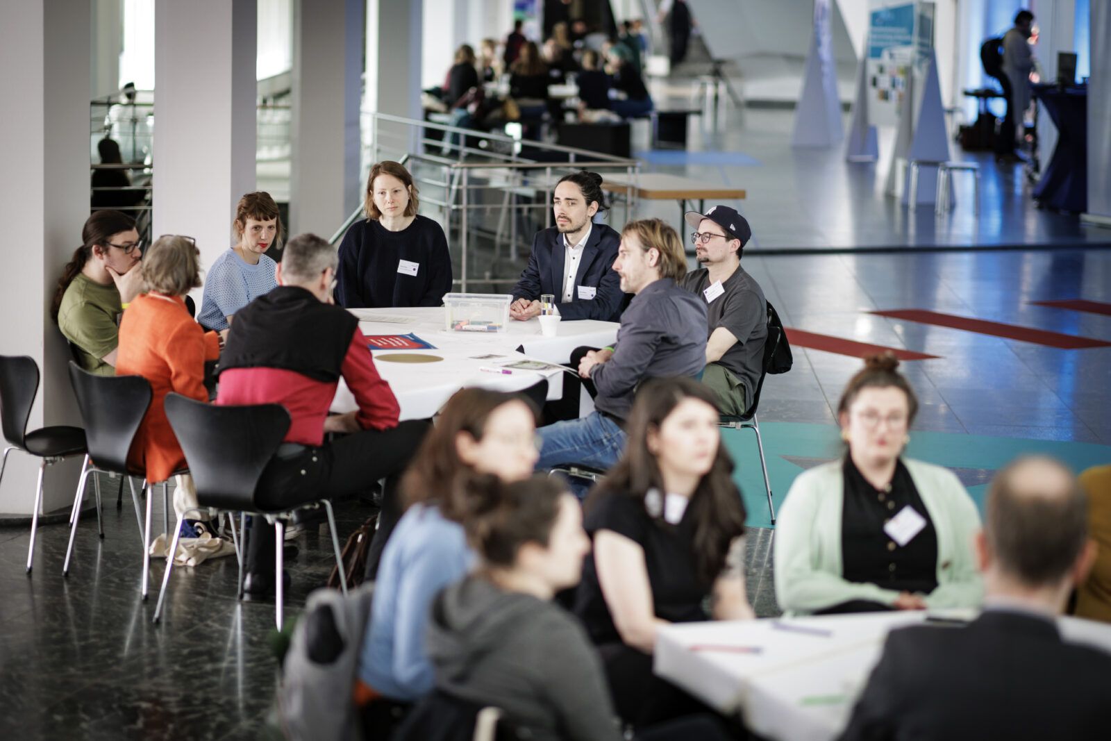 Ein lockerer Arbeitsatmosphäre sitzen mehrere Personen im Berliner Kulturforum um Tische herum.