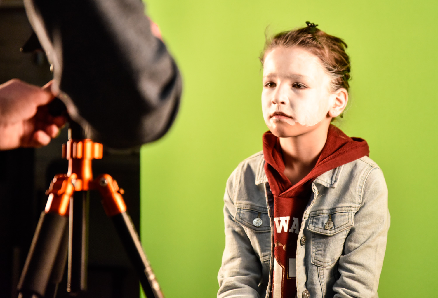 Ein geschminktes Kind sitzt vor der Kamera.