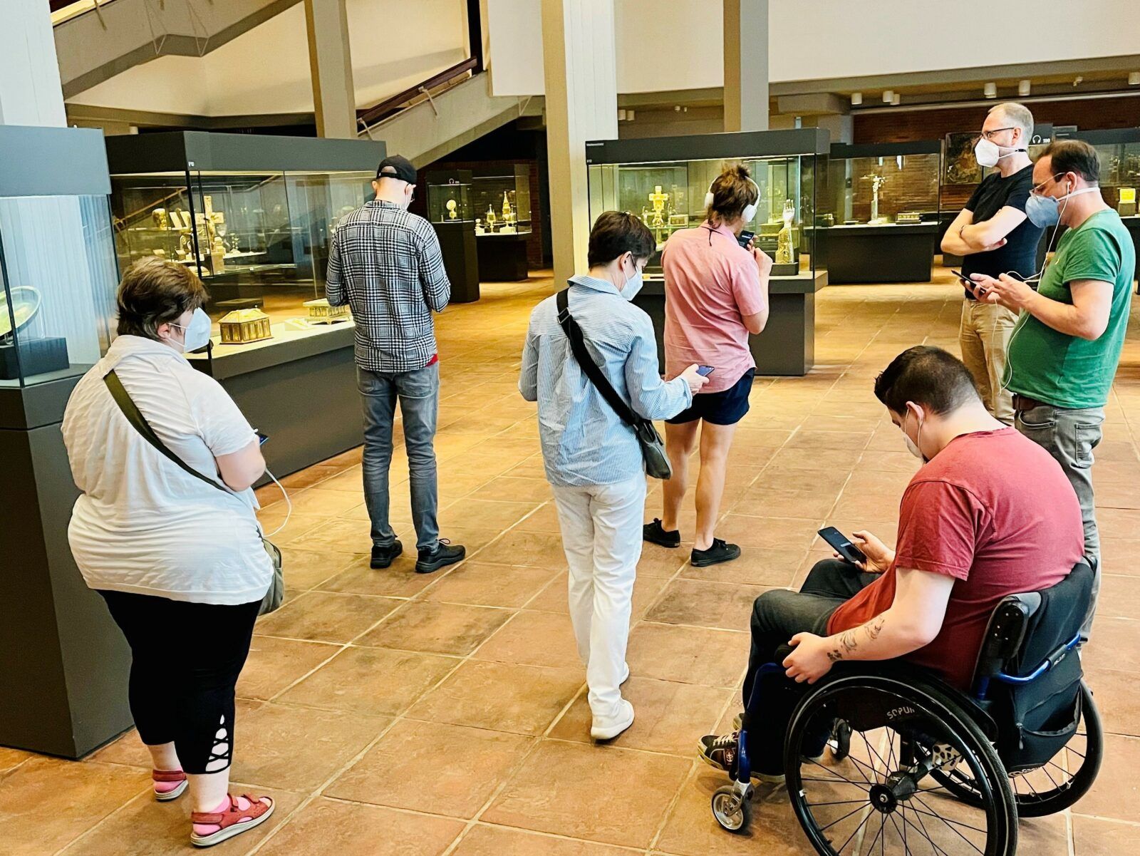 Sieben Personen sind in einer Ausstellung und agieren mit ihren Handys.