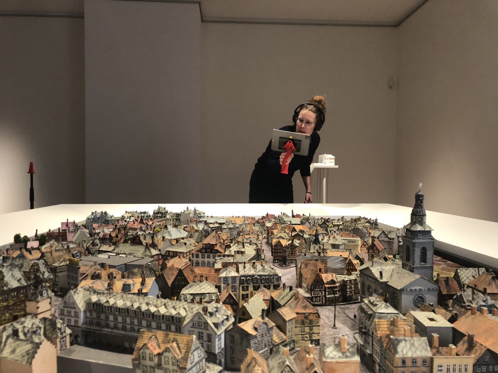 Das Foto zeigt eine Frau, die am Gießener Stadtmodell steht und ein Ipad in der Hand hat, auf das sie schaut.