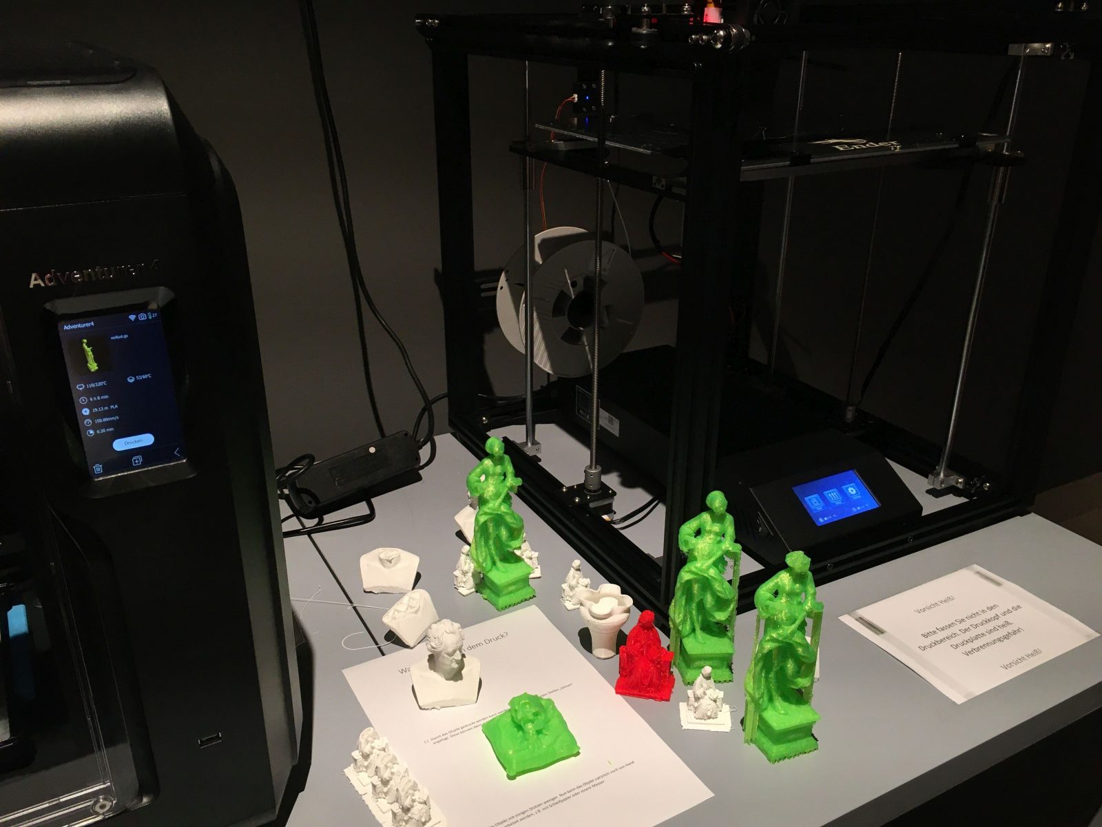 Zwei 3D-Drucker mit verschiedenfarbigen kleinen 3D-Drucken.