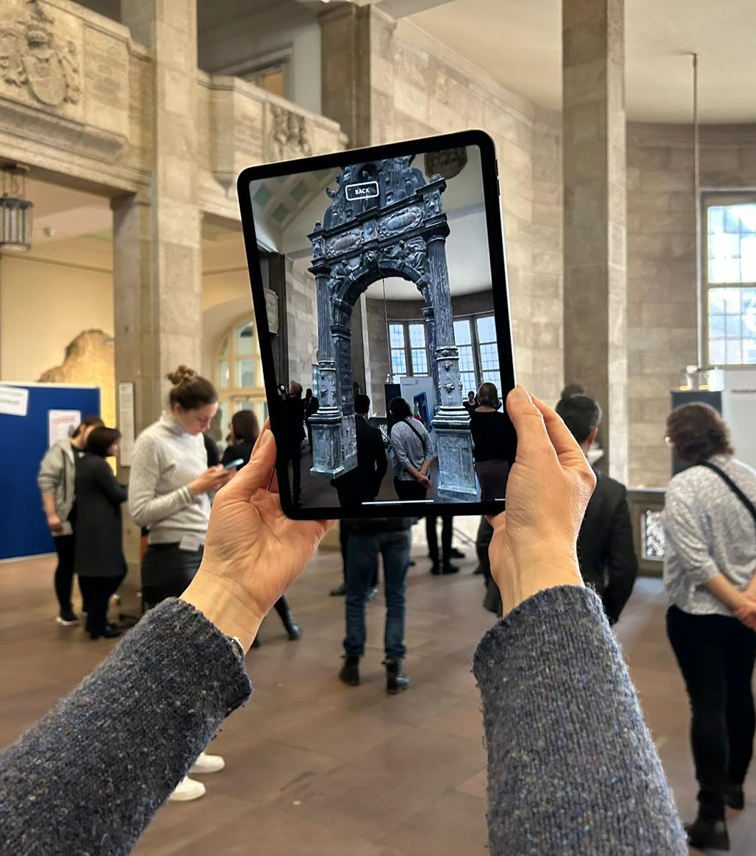 Zu sehen ist ein Tablet, das ein virtuelles Tor im Raum zeigt.