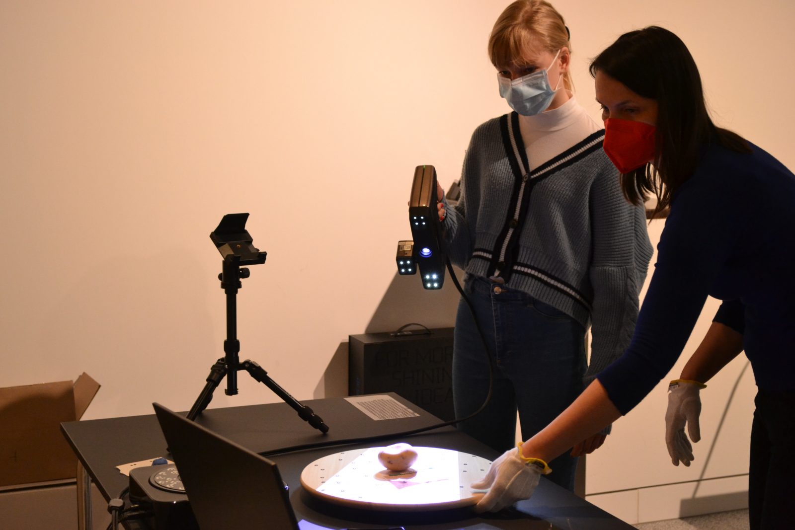 Zwei Personen scannen zusammen ein Objekt. Die Schülerin richtet dabei den Handscanner auf das Objekt, der Lichtstrahl ist zu sehen.