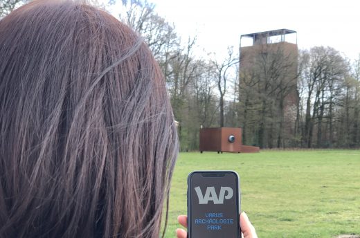 Eine Frau steht mit einem Handy im Museumspark.